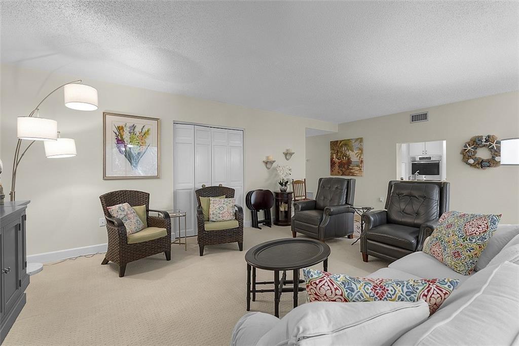 A living room features beige carpeting, a white sofa, wicker chairs, and leather recliners — INDIAN RIVER SHORES, FL