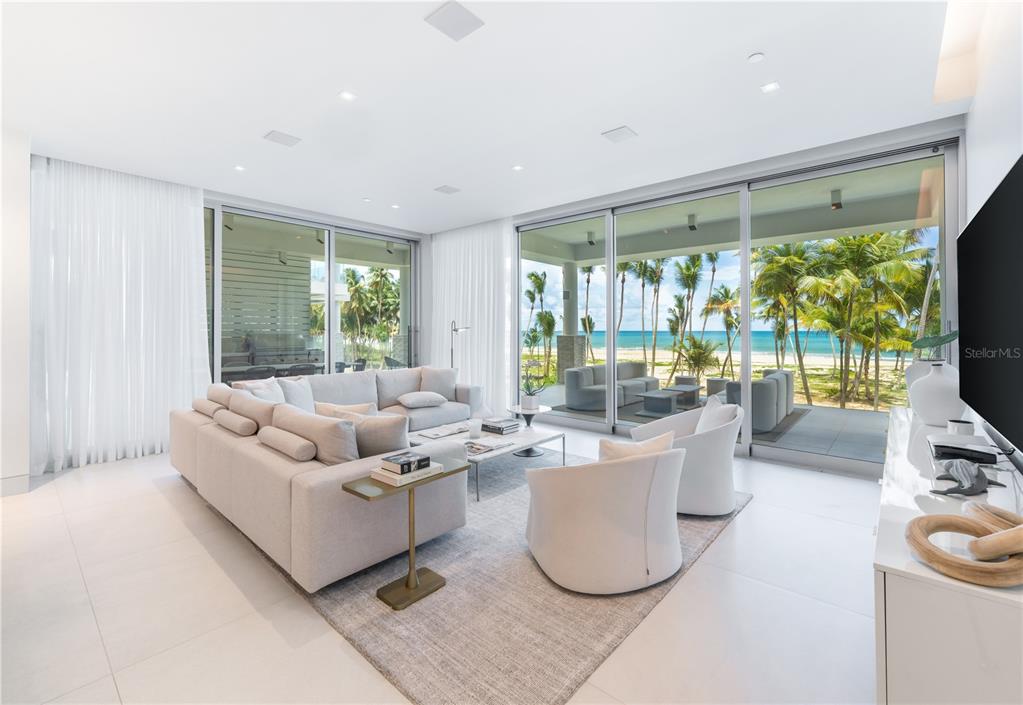 A modern living room features a large sectional sofa, white armchairs, and floor-to-ceiling ocean views — Ocean Drive FOUR SEASONS PRIVATE RESIDENCES UNIT 6302, RIO GRANDE, PR