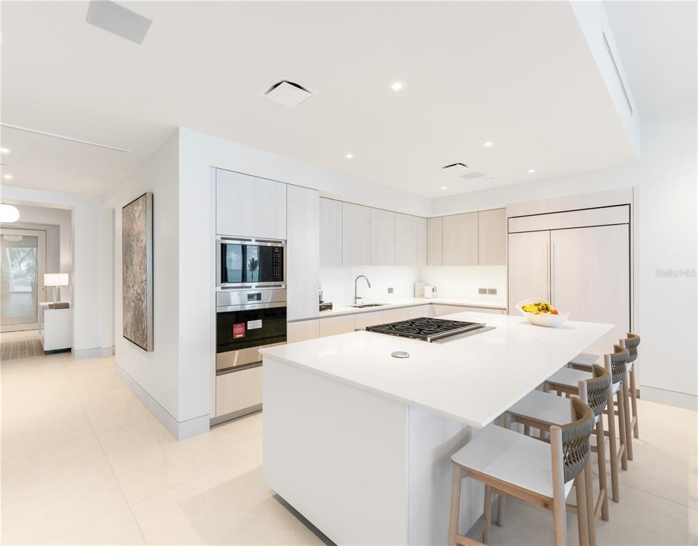 A modern kitchen features white cabinetry, a large island with a cooktop, and bar seating — Ocean Drive FOUR SEASONS PRIVATE RESIDENCES UNIT 6302, RIO GRANDE, PR