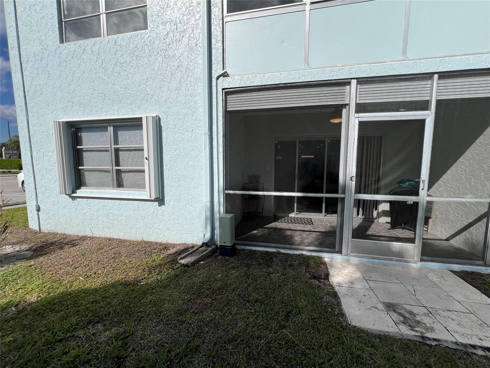 A light blue stucco building exterior features a screened-in patio and a single window — 9780 Marina Boulevard # 415, Boca Raton FL 33428, BOCA RATON, FL