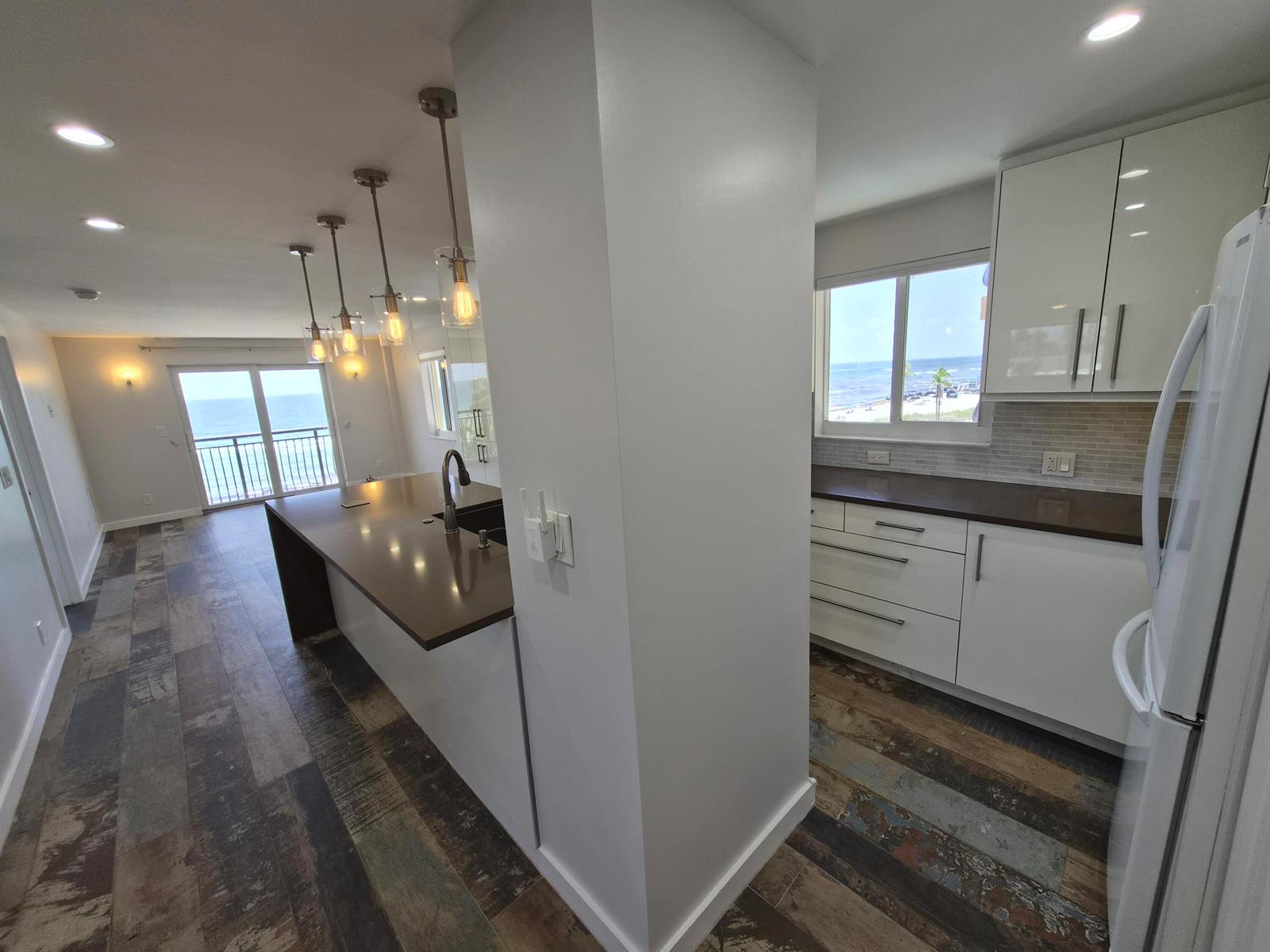 A modern kitchen features white cabinets, dark countertops, and a view of the ocean — 1815 N Surf Road # 404, Hollywood FL 33019, HOLLYWOOD, FL