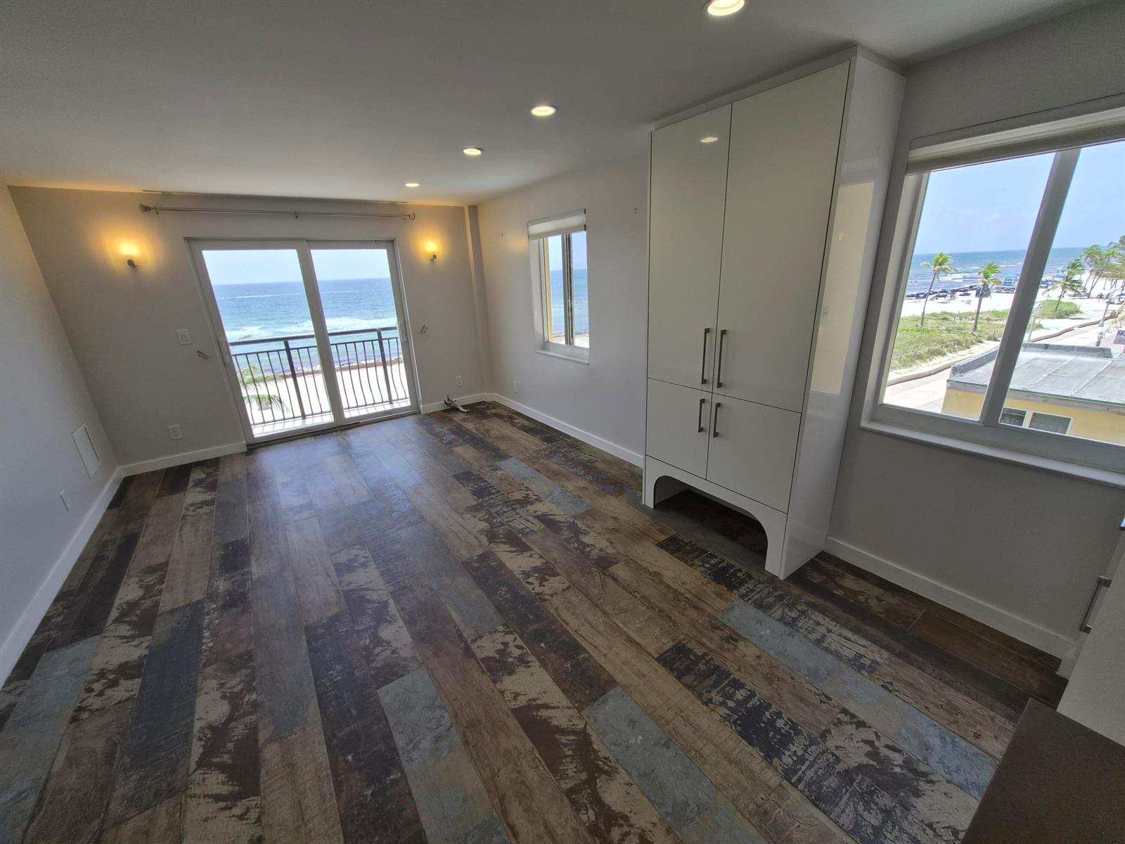 An empty room features wood-look plank flooring, a white storage cabinet, and ocean views — 1815 N Surf Road # 404, Hollywood FL 33019, HOLLYWOOD, FL