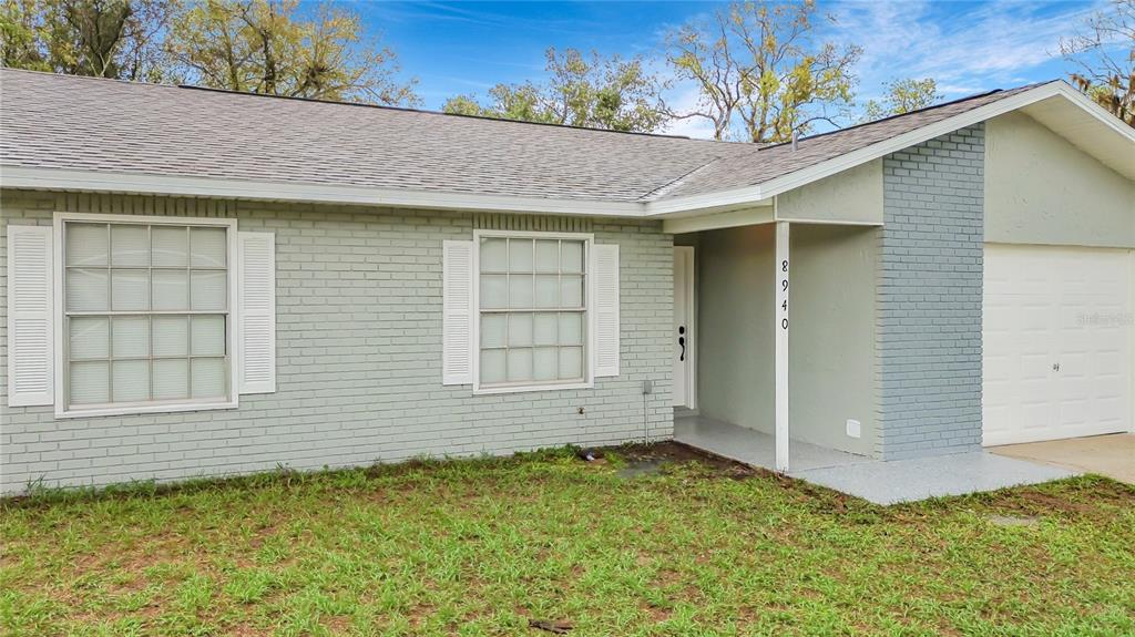 A single-story house with a gray brick exterior, white shutters, and an attached garage — 8940 SE 88TH STREET, OCALA, FL