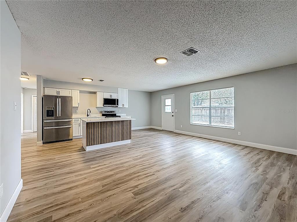 A kitchen with stainless steel appliances and a slatted island opens to a living area — 8940 SE 88TH STREET, OCALA, FL