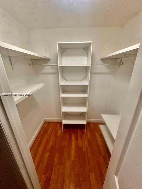 A walk-in closet features white shelving, hanging rods, and wood-look flooring — 10670 SW 156th Pl # 301, Miami FL 33196, MIAMI, FL