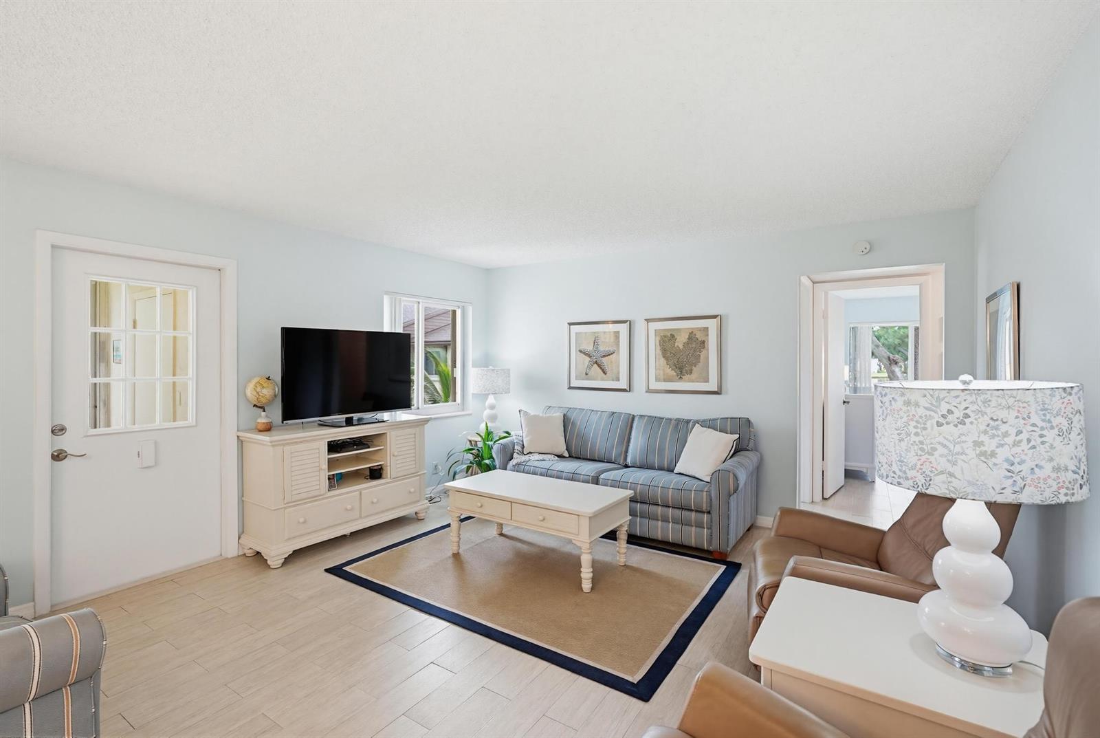 A living room features light blue walls, a striped sofa, a television console, and tile flooring — 119 Lake Pine Circle # 2, FL 33463, FL