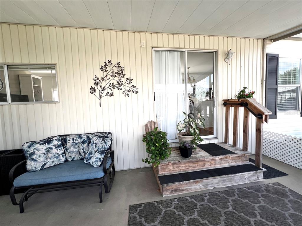 A covered porch features a metal glider, wooden steps, and a sliding glass door — 5316 53RD AVENUE E UNIT R36, BRADENTON, FL