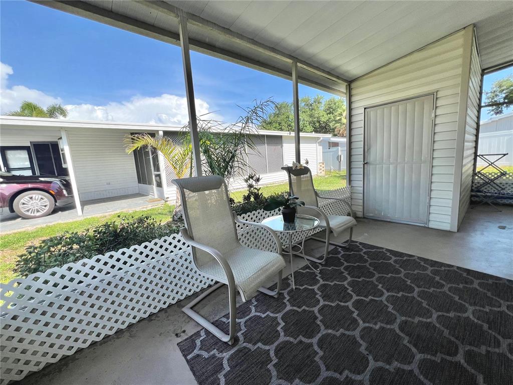 A covered patio features two chairs, a small table, and a patterned rug — 5316 53RD AVENUE E UNIT R36, BRADENTON, FL