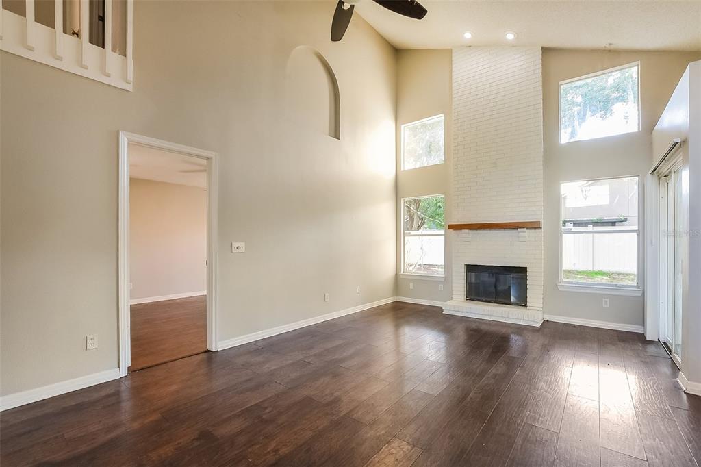 A living room features dark wood floors, a white brick fireplace, and high ceilings — 1347 BLACK WILLOW TRAIL, ALTAMONTE SPRINGS, FL