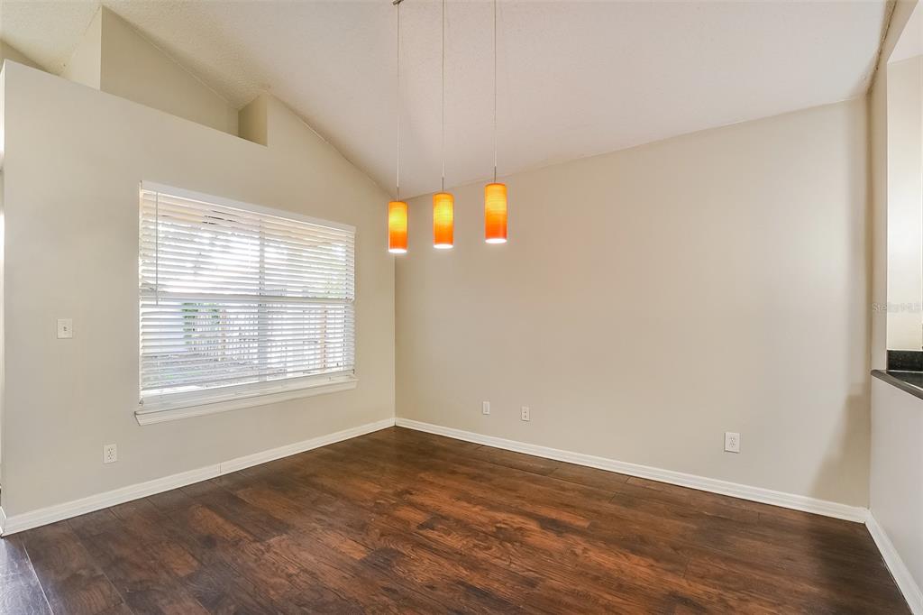 An empty dining room with dark wood floors, a large window, and three pendant lights — 1347 BLACK WILLOW TRAIL, ALTAMONTE SPRINGS, FL