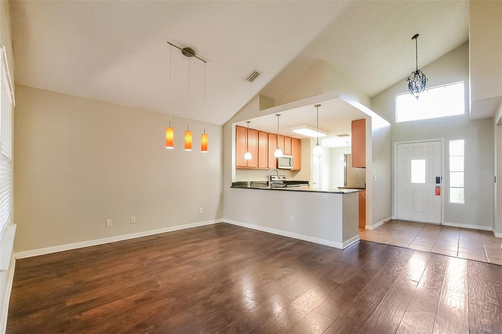 A dining area with wood floors, vaulted ceilings, and a breakfast bar overlooking the kitchen — 1347 BLACK WILLOW TRAIL, ALTAMONTE SPRINGS, FL