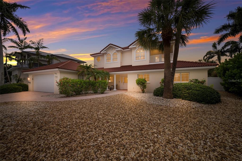 A two-story house with a tile roof, garage, and gravel yard at sunset — 532 70TH STREET, HOLMES BEACH, FL