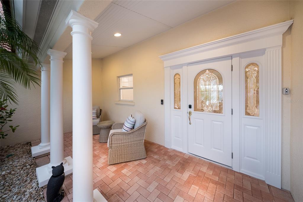 A patio with a pool, spa, and lounge furniture overlooks a canal with a boat — 532 70TH STREET, HOLMES BEACH, FL
