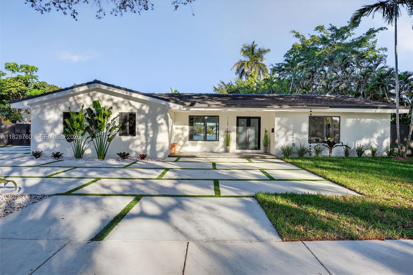 A single-story white house features a modern concrete paver driveway with grass inlays — 7101 E Troon Cir, Miami Lakes FL 33014, MIAMI LAKES, FL