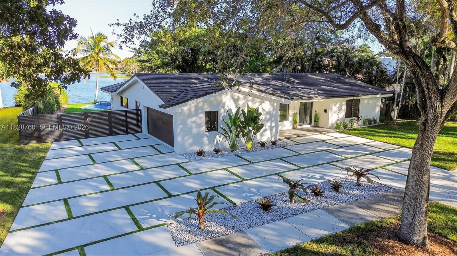 A single-story house with a white exterior, dark roof, and a grid-patterned concrete driveway — 7101 E Troon Cir, Miami Lakes FL 33014, MIAMI LAKES, FL