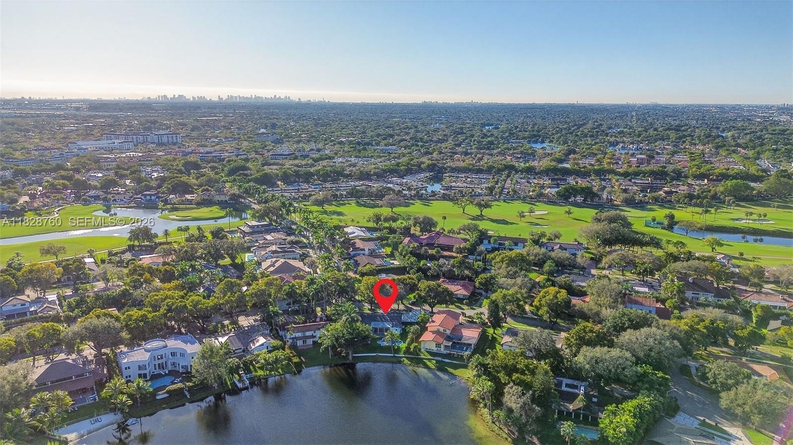 An aerial view shows a residential neighborhood with a lake and a golf course — 7101 E Troon Cir, Miami Lakes FL 33014, MIAMI LAKES, FL