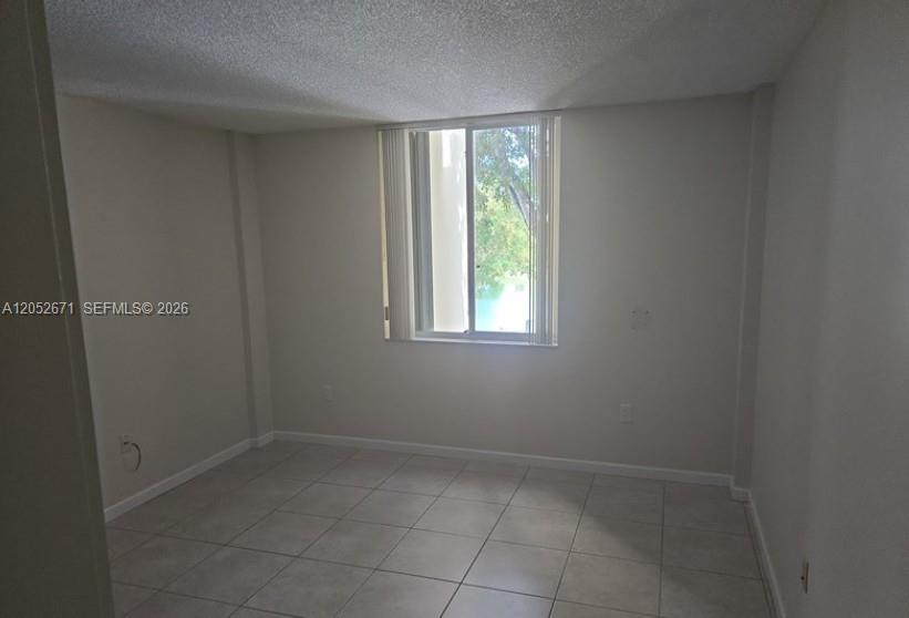 An open living area with white tile floors leads to a kitchen with wood cabinets — 6861 SW 147th Ave # 3G, Miami FL 33193, MIAMI, FL