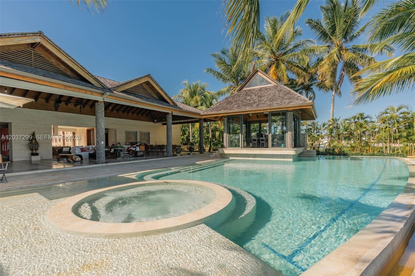 A swimming pool with an integrated hot tub sits beside a house with a gazebo — 0 Cap Cana, FL, FL