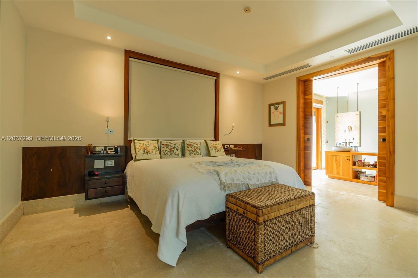 A bedroom features a bed with floral pillows, a wicker chest, and an adjacent bathroom — 0 Cap Cana, FL, FL