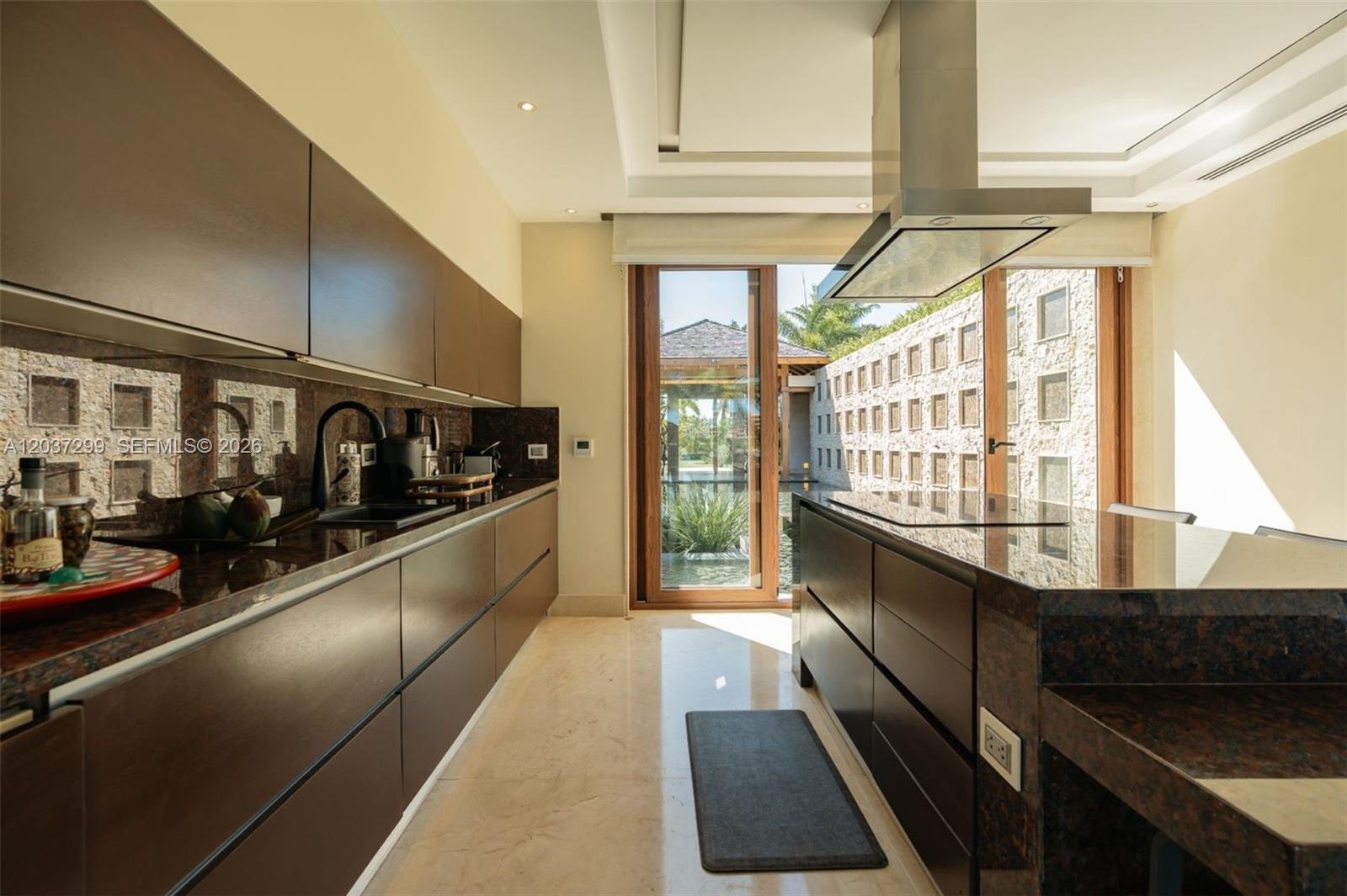 A modern kitchen features dark wood cabinetry, granite countertops, and a view of an outdoor courtyard — 0 Cap Cana, FL, FL
