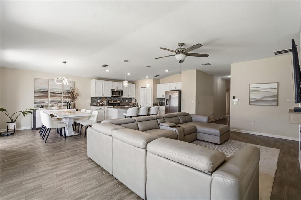 An open-concept living room and kitchen featuring a large sectional sofa and dining area — 4230 HOLSTEIN STREET, ST CLOUD, FL