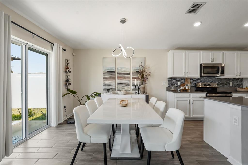 A dining area with a white table, six chairs, and a modern light fixture — 4230 HOLSTEIN STREET, ST CLOUD, FL