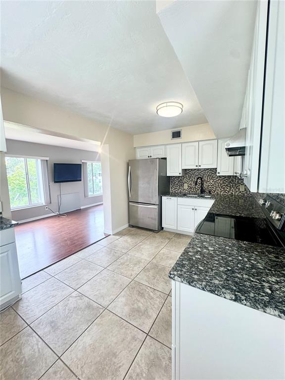 A kitchen with white cabinets and granite countertops opens into a living area with flooring — 2020 WORLD PARKWAY BOULEVARD UNIT 54, CLEARWATER, FL