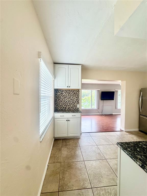 A kitchen area features white cabinets, a mosaic tile backsplash, and light-colored floor tiles — 2020 WORLD PARKWAY BOULEVARD UNIT 54, CLEARWATER, FL