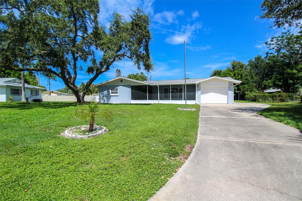 A single-story house with a screened-in porch, a concrete driveway, and a large front yard — 2521 BISMARK WAY, SARASOTA, FL
