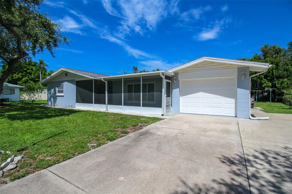 A light blue single-story house with a screened-in porch and a white garage door — 2521 BISMARK WAY, SARASOTA, FL