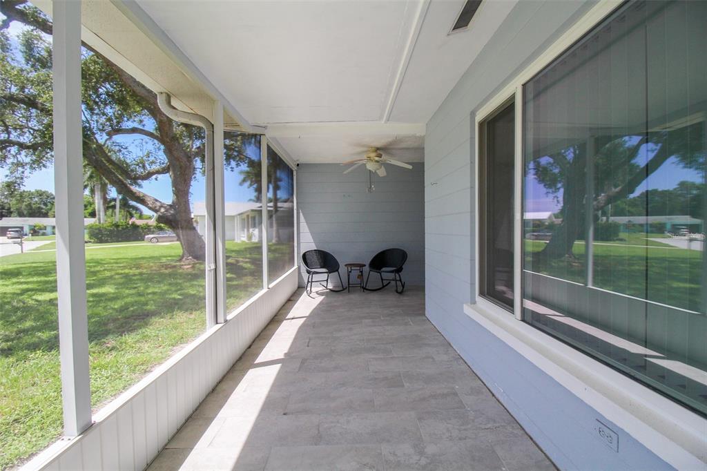 A screened-in porch with light gray tile flooring, a ceiling fan, and two outdoor chairs — 2521 BISMARK WAY, SARASOTA, FL