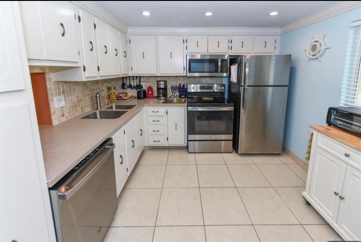 A kitchen with white cabinets, stainless steel appliances, tile flooring, and a tiled backsplash — 2615 NE 3rd Court # 217, Boynton Beach FL 33435, BOYNTON BEACH, FL