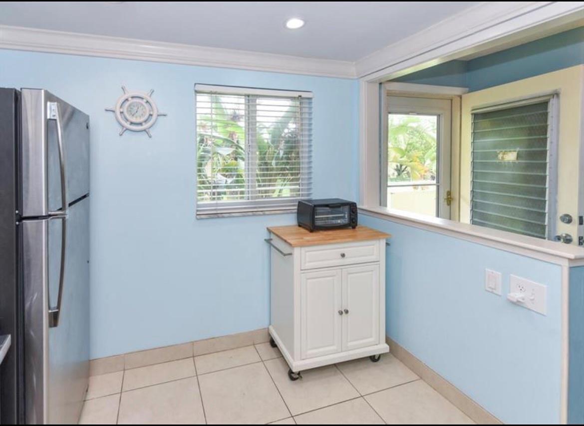 A kitchen with light blue walls, tile flooring, a stainless refrigerator, and a rolling island — 2615 NE 3rd Court # 217, Boynton Beach FL 33435, BOYNTON BEACH, FL