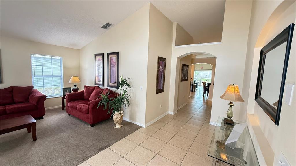 A living room with red sofas and a tiled entryway with a glass console table — 7979 MAGNOLIA BEND COURT, KISSIMMEE, FL