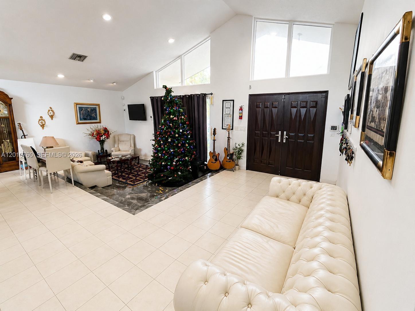 A spacious living room features a vaulted ceiling, tiled floors, a Christmas tree, and furniture — 10500 SW 126th St, Miami FL 33176, MIAMI, FL