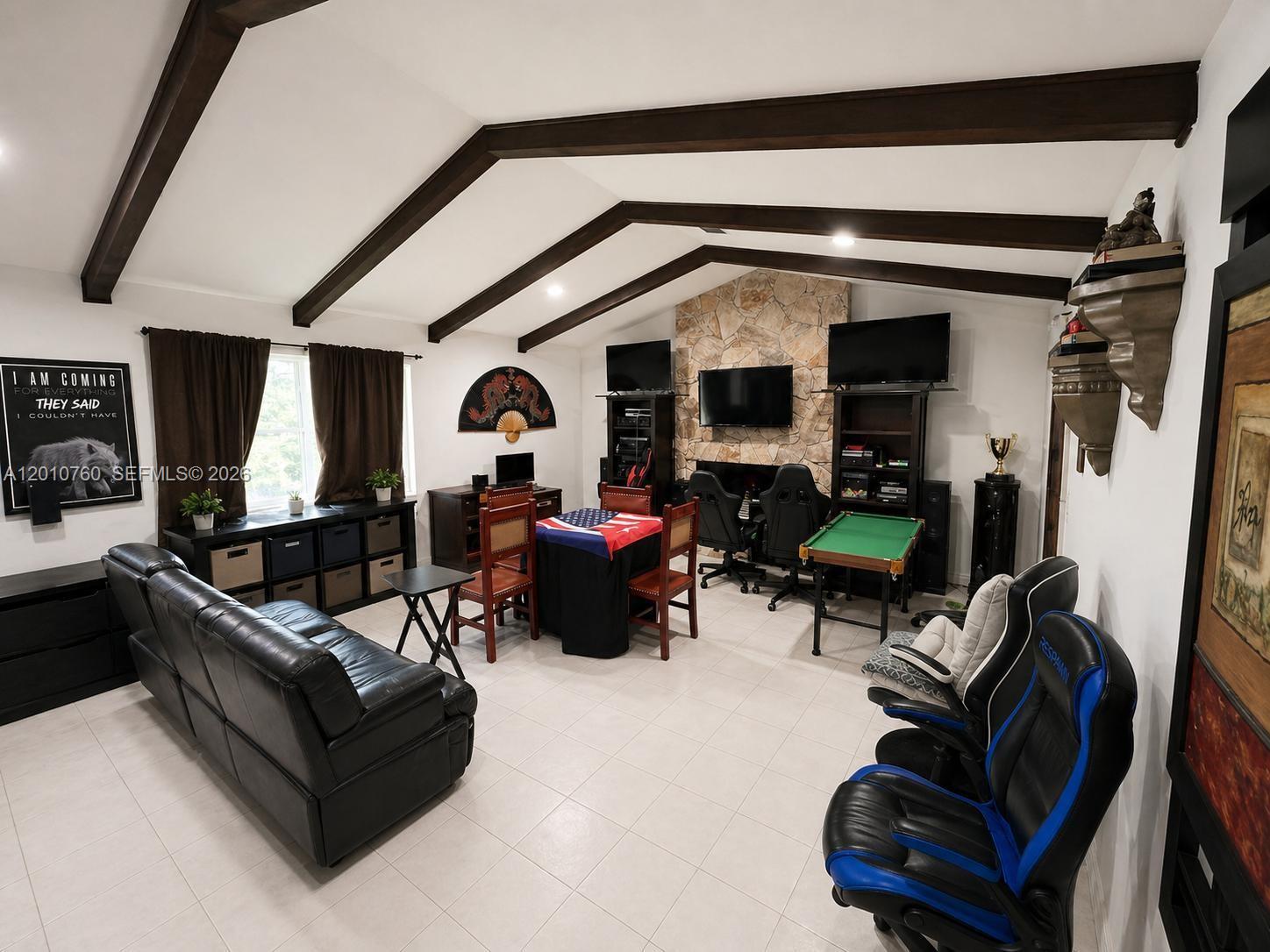 A living room features vaulted ceilings with exposed beams, a stone fireplace, and gaming furniture — 10500 SW 126th St, Miami FL 33176, MIAMI, FL