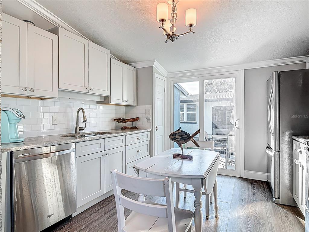 A kitchen with white cabinets, stainless steel appliances, and a small dining table near sliding doors — 85 HEATHER POINT COURT UNIT 850, NEW SMYRNA BEACH, FL