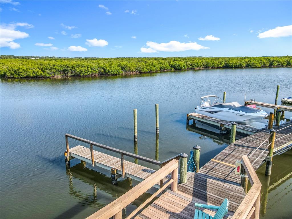 A wooden dock extends into a calm waterway with a boat moored alongside — 85 HEATHER POINT COURT UNIT 850, NEW SMYRNA BEACH, FL