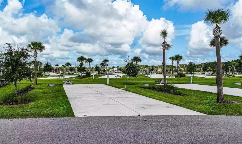 A paved RV campsite features a picnic table, palm trees, and green grass — 96 CR-630 E, LAKE WALES, FL