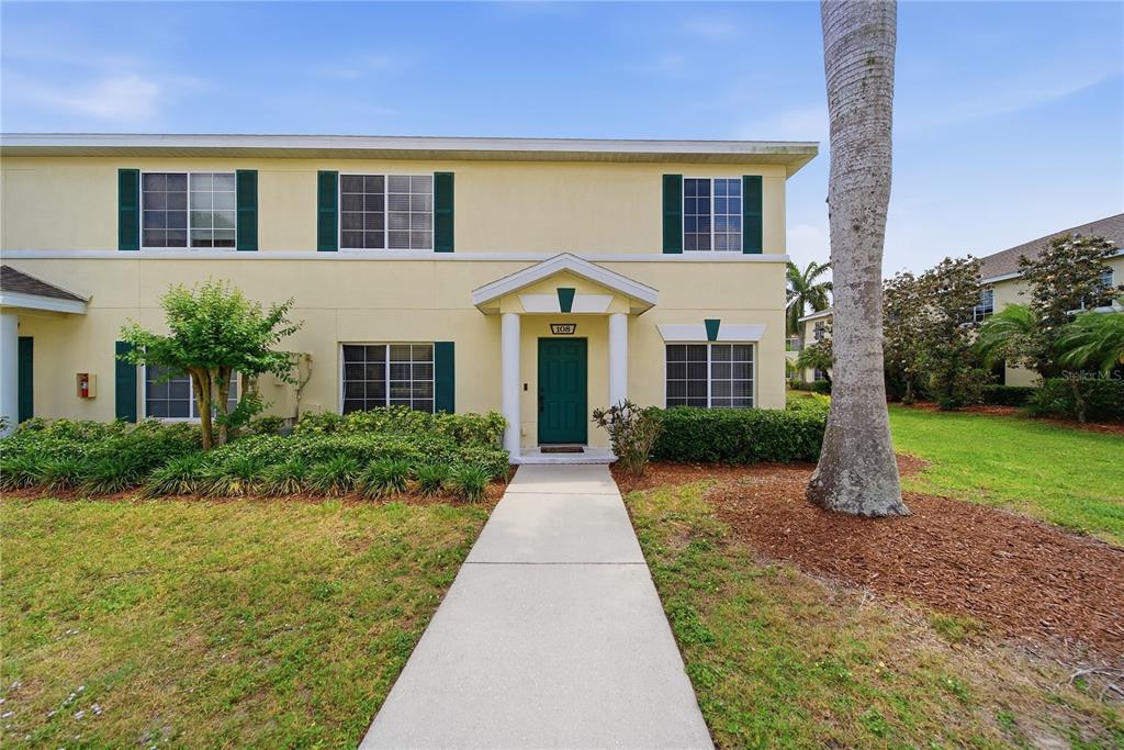 A two-story yellow townhouse with a green front door and a concrete walkway — 335 CAPE HARBOUR LOOP UNIT 108, BRADENTON, FL