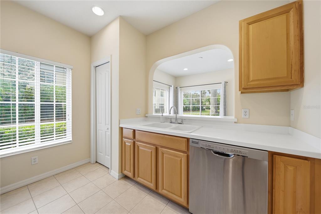 A kitchen features light wood cabinets, white countertops, a stainless steel dishwasher, and a window — 335 CAPE HARBOUR LOOP UNIT 108, BRADENTON, FL
