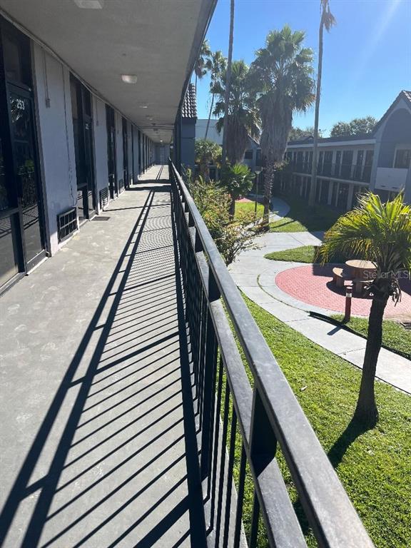 An elevated outdoor walkway overlooks a courtyard with palm trees, a circular patio, and buildings — 8421 S ORANGE BLOSSOM TRAIL UNIT 254, ORLANDO, FL
