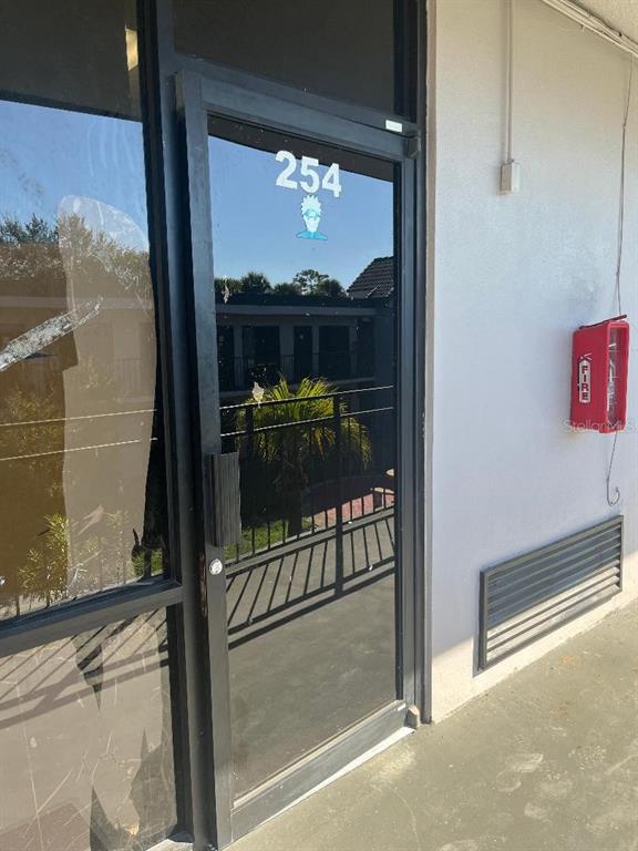 A glass door labeled 254 with a fire extinguisher mounted on the adjacent exterior wall — 8421 S ORANGE BLOSSOM TRAIL UNIT 254, ORLANDO, FL