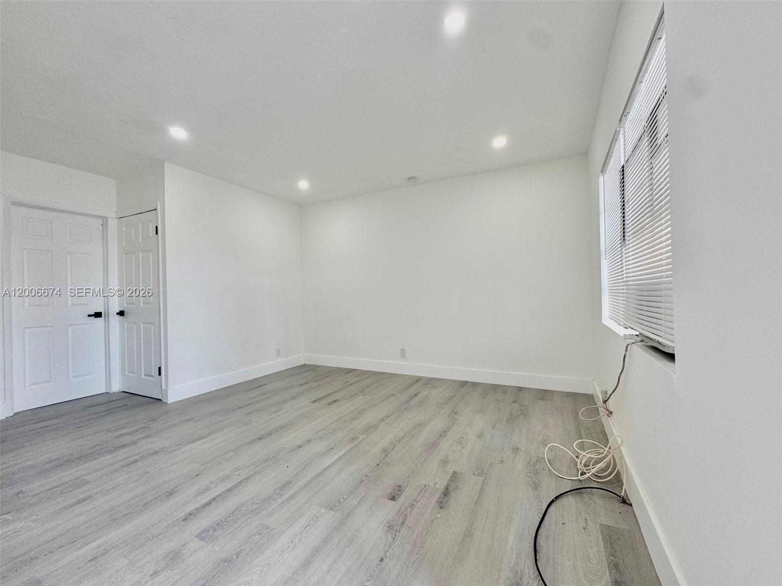 An empty room features white walls, recessed lighting, and light gray wood-look flooring — 417 NW 2nd Ave # 000, Hallandale Beach FL 33009, HALLANDALE BEACH, FL