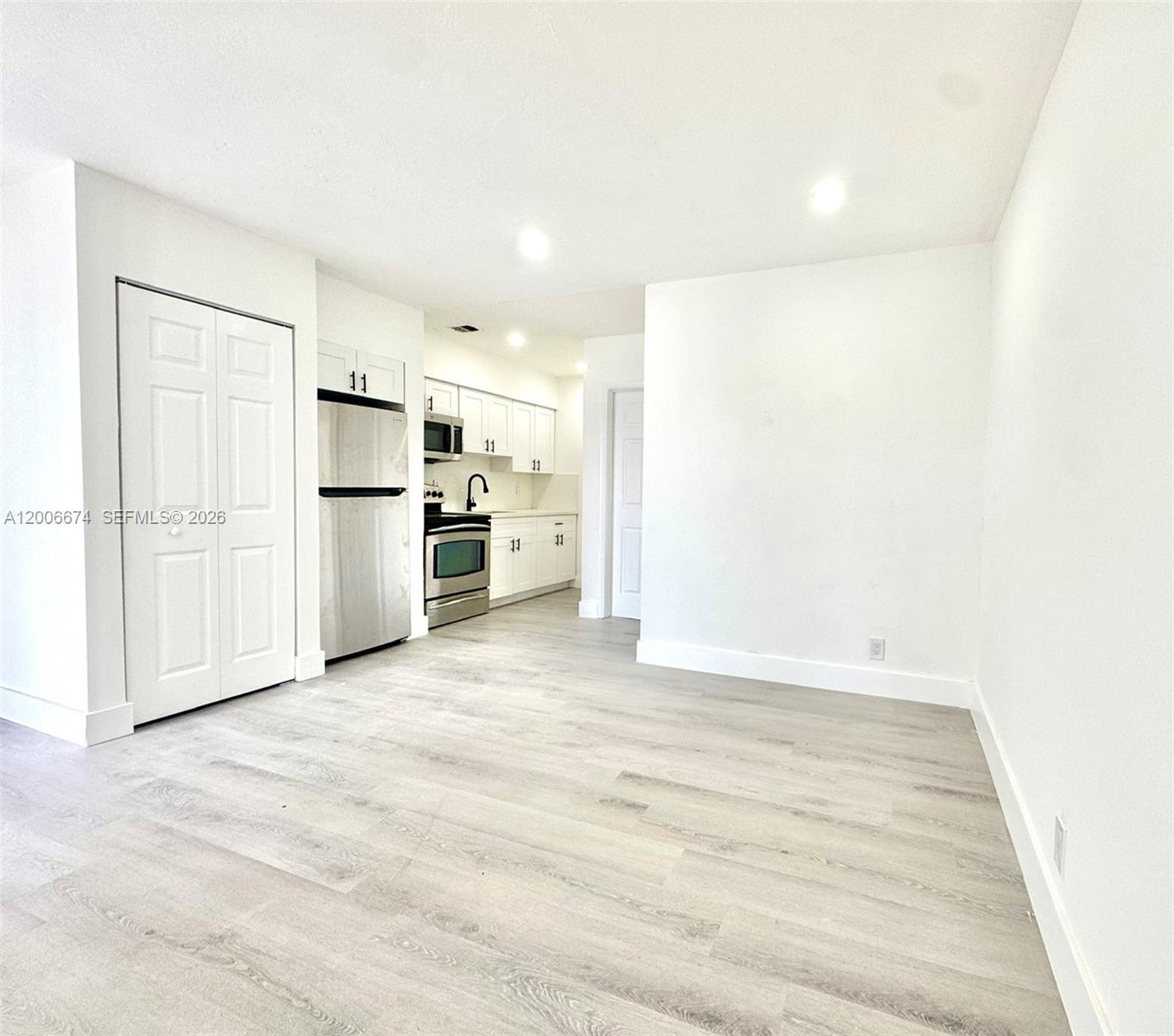 This room features light wood-look flooring, white walls, and an open-concept kitchen with stainless appliances — 417 NW 2nd Ave # 000, Hallandale Beach FL 33009, HALLANDALE BEACH, FL