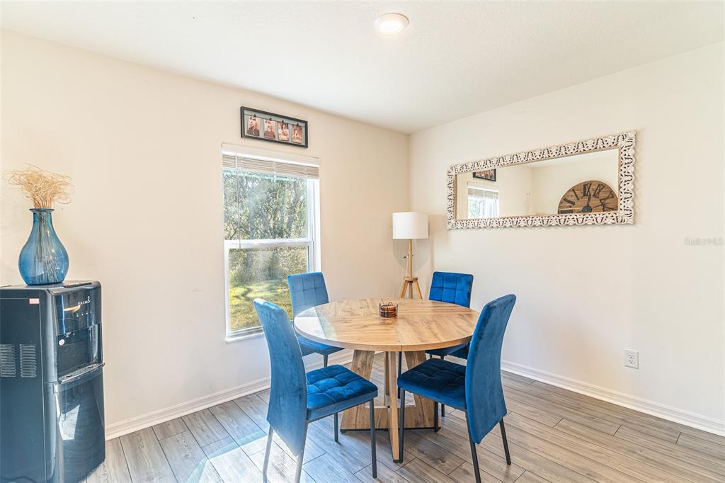 A dining area features a round wooden table, four blue chairs, and a large wall mirror — 437 RIO GRANDE PLACE, POINCIANA, FL