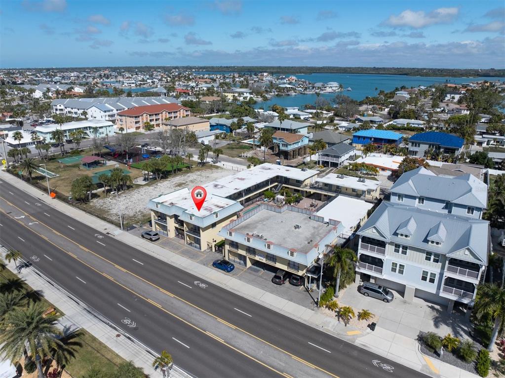 An aerial view of a multi-story apartment building located along a coastal road — 16333 GULF BOULEVARD UNIT 201, REDINGTON BEACH, FL