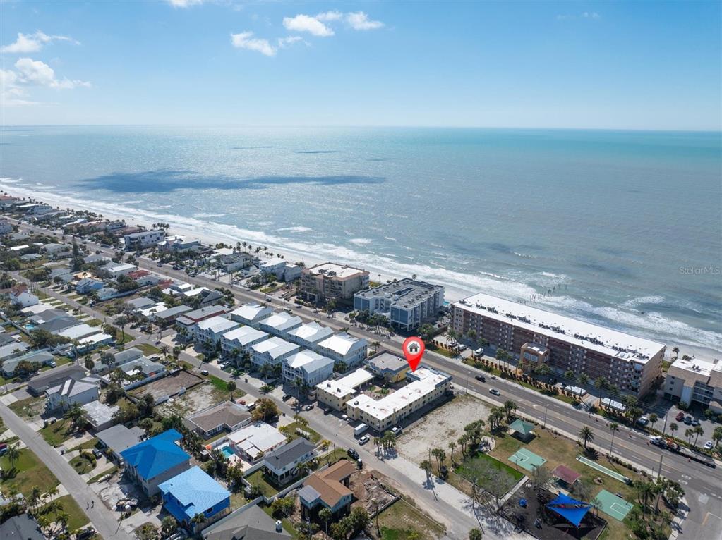An aerial view shows a coastal neighborhood with a marked multi-story building near the beach — 16333 GULF BOULEVARD UNIT 201, REDINGTON BEACH, FL