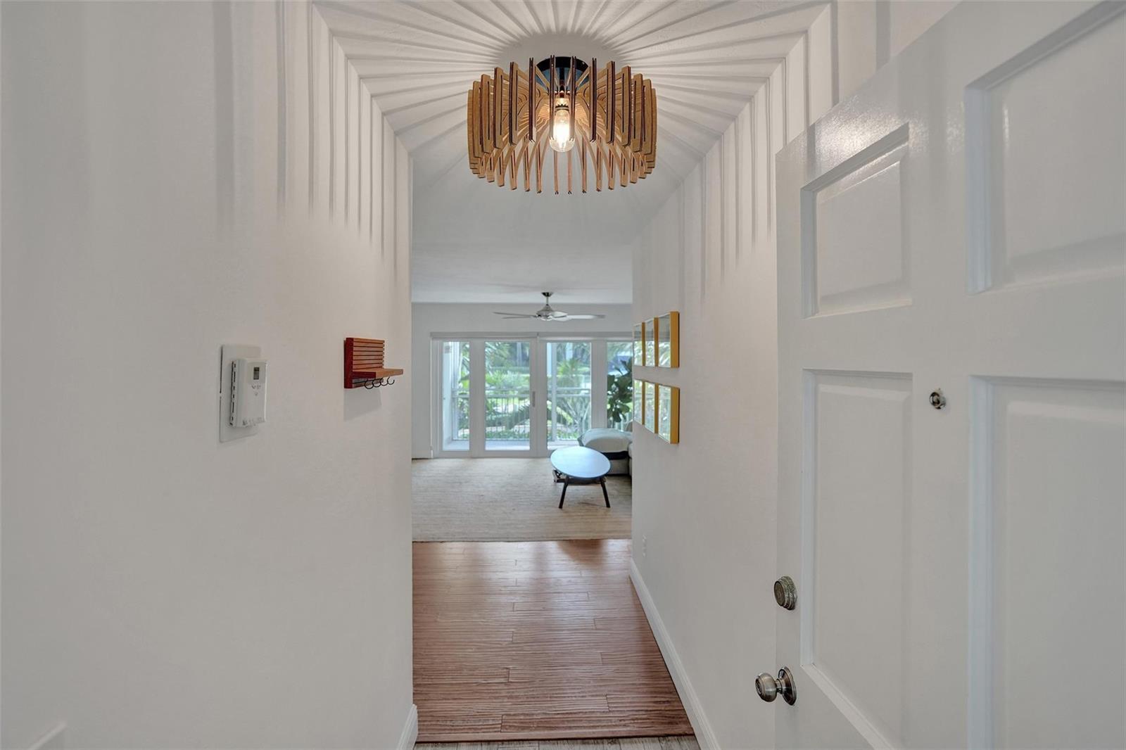 A white entryway leads into a living room with wood flooring and a slatted light fixture — 2501 S Ocean Boulevard # 1030, Boca Raton FL 33432, BOCA RATON, FL