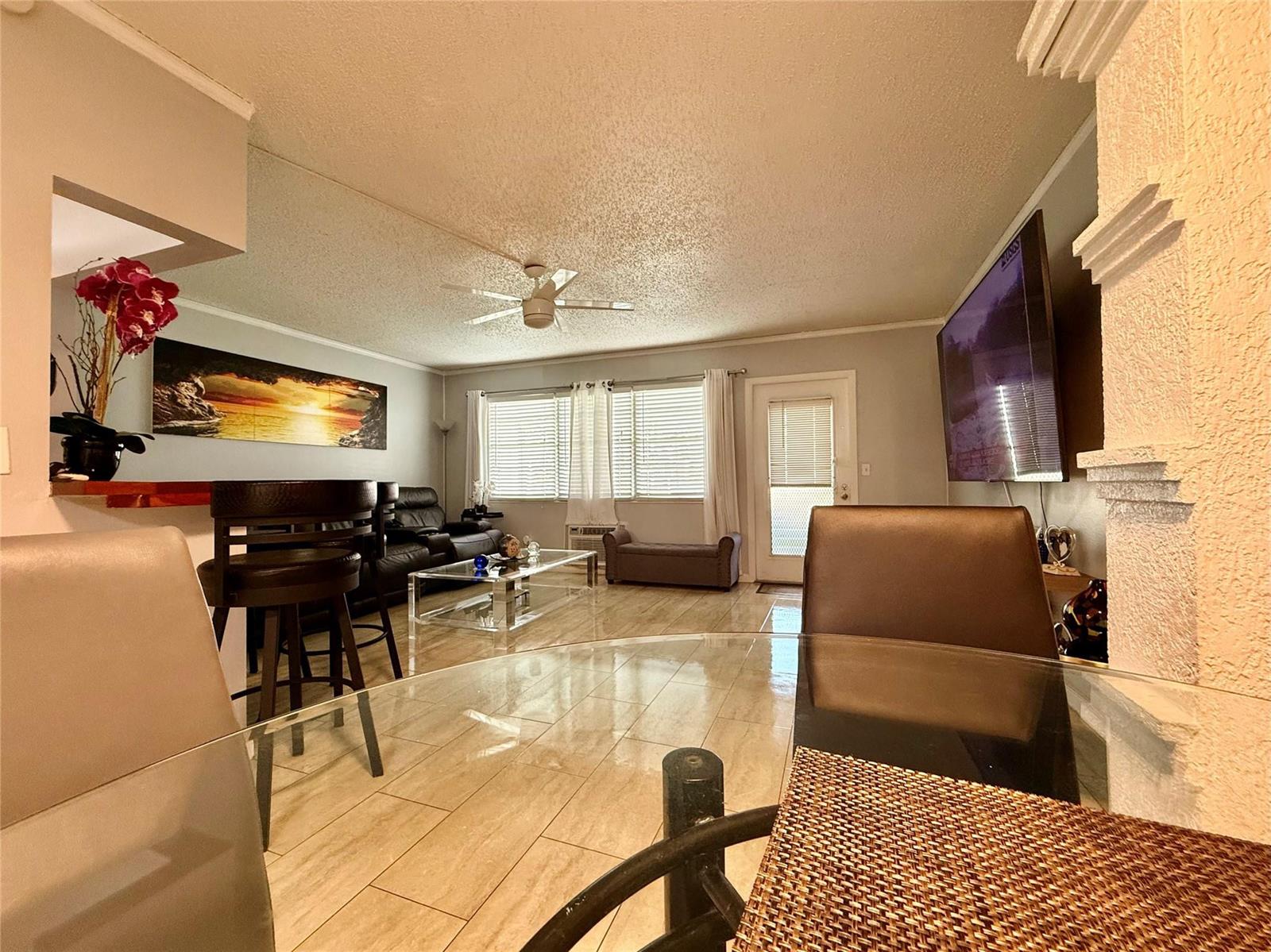 A living room with tile floors, a ceiling fan, a glass coffee table, and bar seating — 355 Oakridge T # 355, Deerfield Beach FL 33442, DEERFIELD BEACH, FL